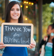 woman holding sign that says Thank you for buying local