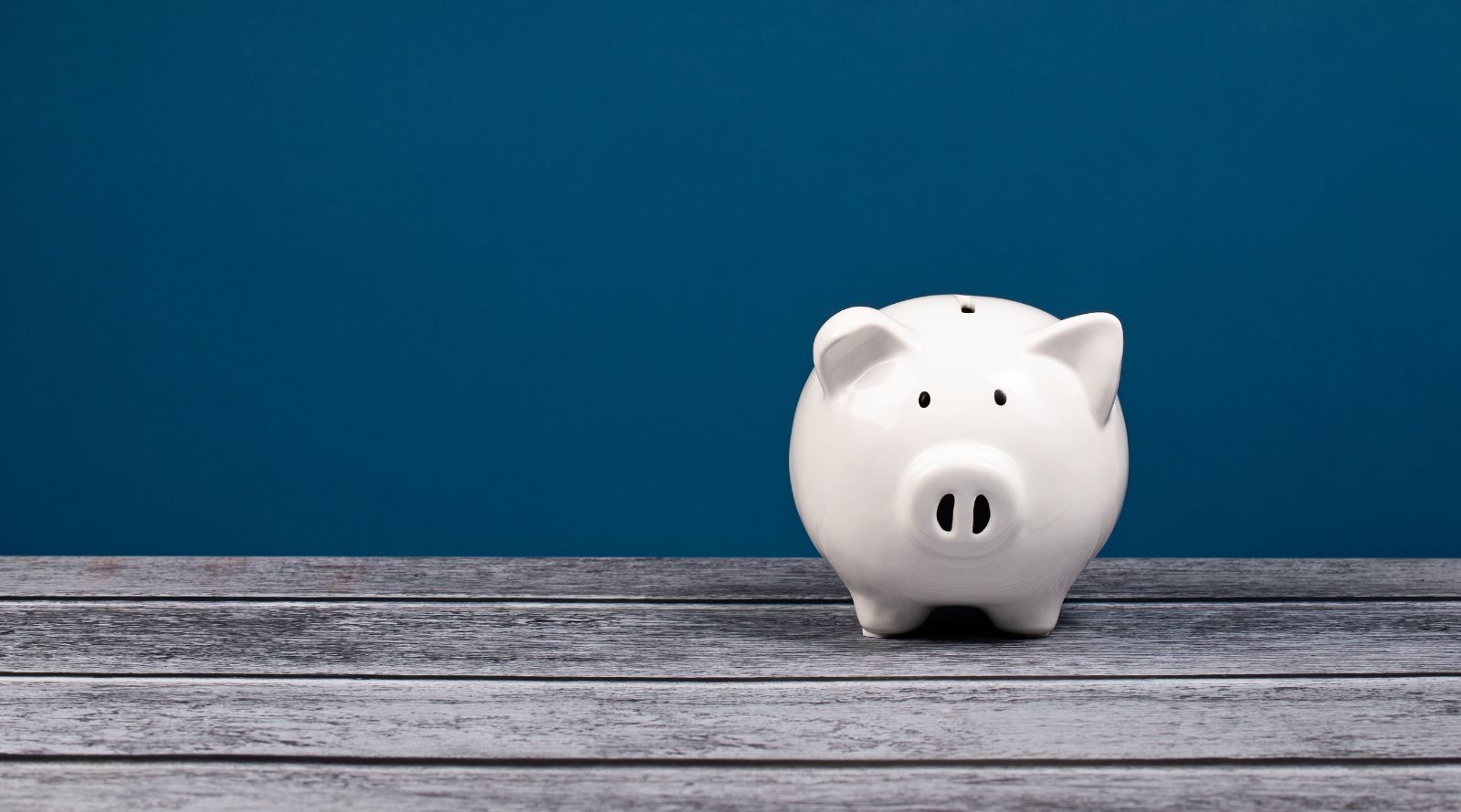 white piggy bank with blue background on wood