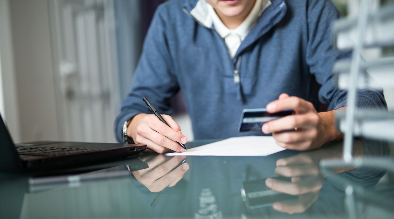 person with debit card writing on paper